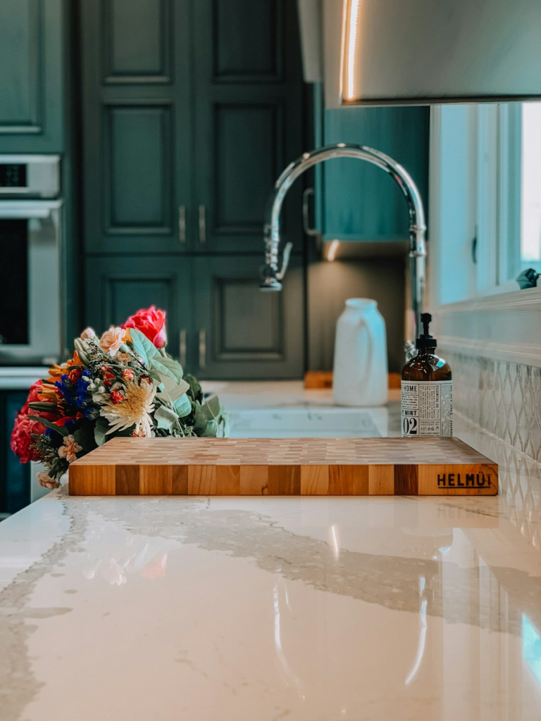 White and gray mitered quartz kitchen countertops with a matching full-height backsplash and mint shaker cabinets in Snellville by Atlanta Granite Pros.